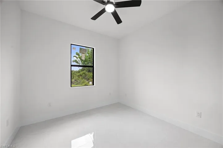 Bright room featuring a ceiling fan with light, white walls, and light-toned tile flooring
