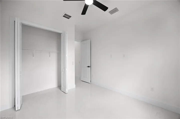 Room featuring light-toned flooring, white walls, and a ceiling fan