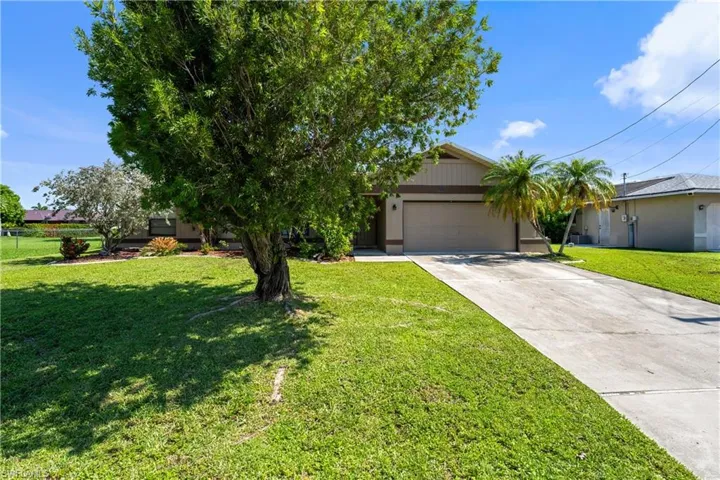 View of front of property with concrete driveway, a front lawn, and a garage