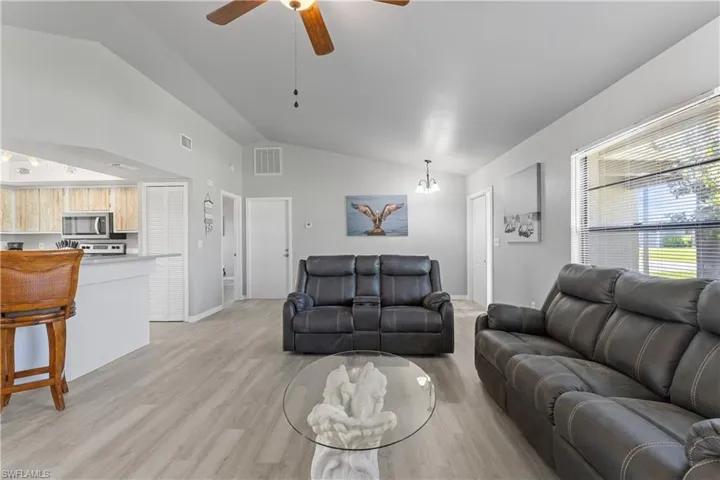 Living area with lofted ceiling, light wood finished floors, and ceiling fan