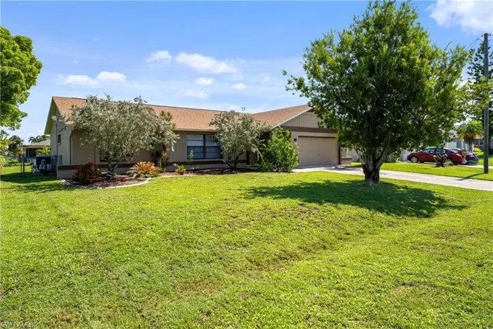 View of front of home with driveway, a garage, and a front lawn