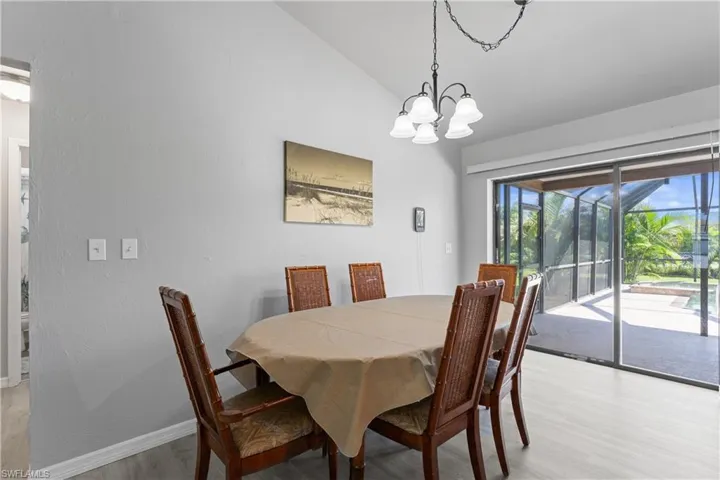 Dining space with light wood-type flooring, a chandelier, and vaulted ceiling
