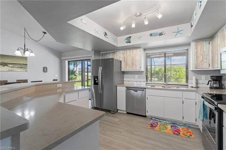 Kitchen featuring appliances with stainless steel finishes, light wood-style floors, a chandelier, and plenty of natural light