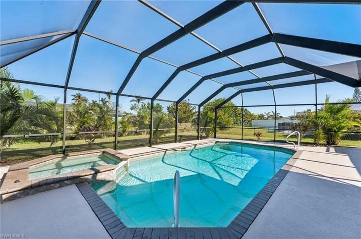 View of swimming pool featuring a pool with connected hot tub, a patio area, and a lanai
