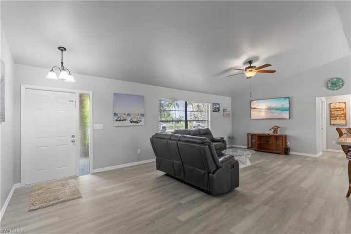 Living area featuring light wood-style floors, lofted ceiling, and ceiling fan