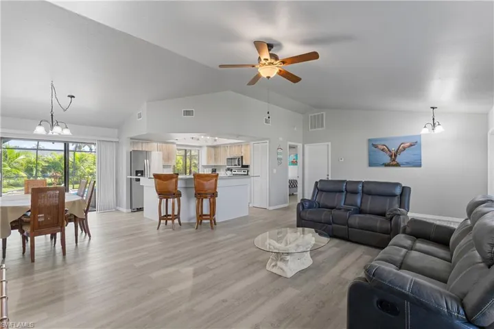 Living room with a chandelier, lofted ceiling, ceiling fan, and healthy amount of natural light