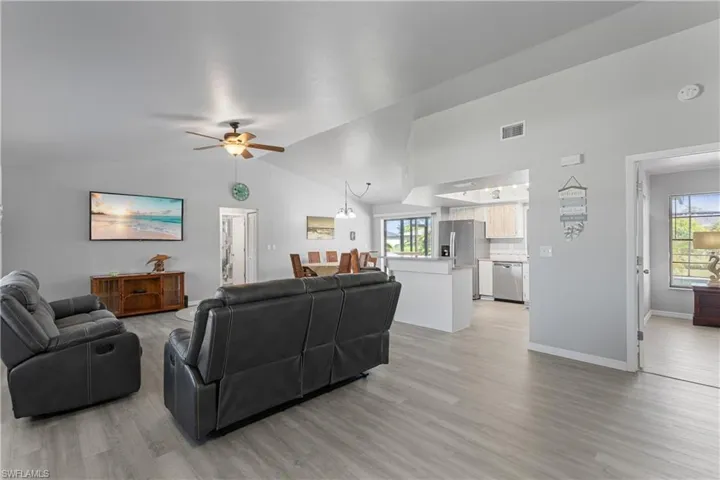 Living room with a ceiling fan, light wood-type flooring, and high vaulted ceiling