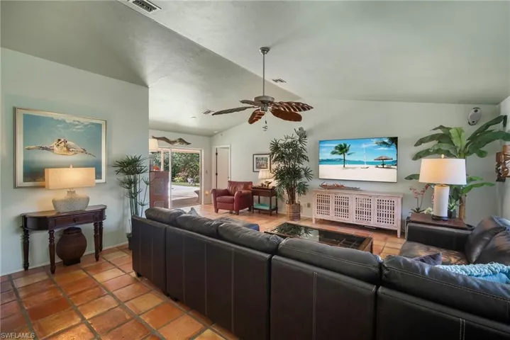 Living room featuring ceiling fan, tile patterned flooring, and vaulted ceiling