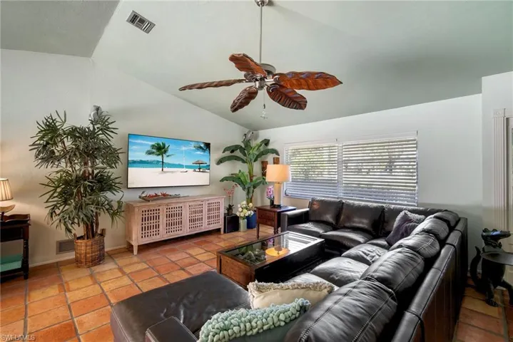 Tiled living room featuring ceiling fan and vaulted ceiling