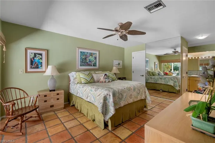 Bedroom with ensuite bathroom, tile patterned floors, and ceiling fan