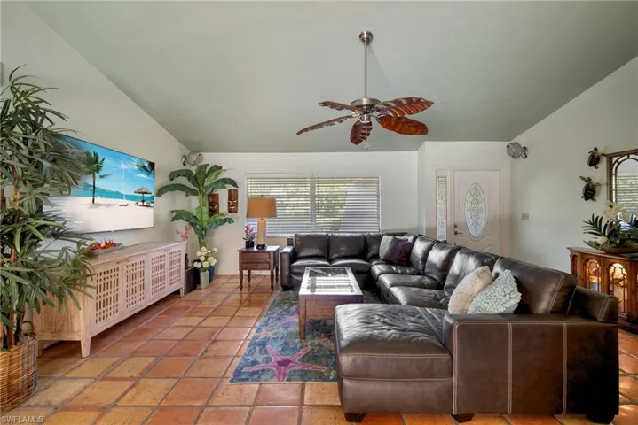 Tiled living room featuring ceiling fan and lofted ceiling