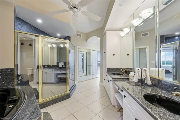Full bathroom with toilet, double vanity, a bath, a shower stall, and tile patterned floors