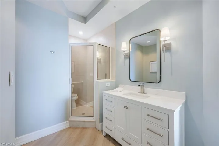 Bathroom featuring baseboards, vanity, a stall shower, toilet, and recessed lighting
