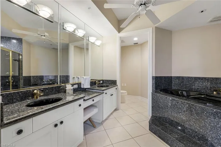 Full bath featuring a ceiling fan, tile patterned flooring, a bath, and toilet