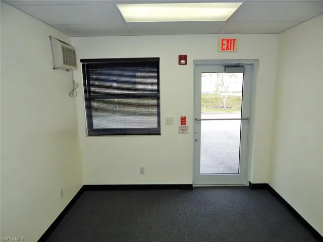 Spare room featuring a wall mounted AC and dark carpet