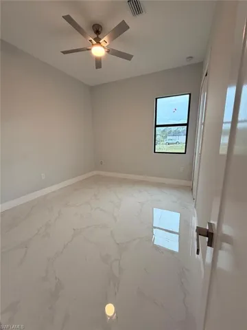Empty room with light marble finish floors and ceiling fan