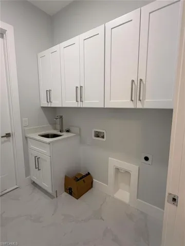 Laundry area with light marble finish floors, washer hookup, cabinet space, and hookup for an electric dryer