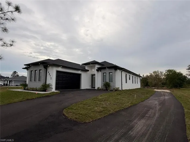 Prairie-style home with asphalt driveway, stucco siding, and a front lawn