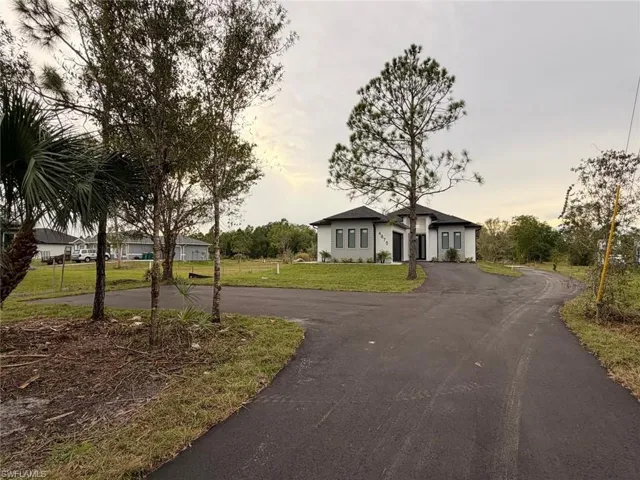 Ranch-style home with driveway and a lawn