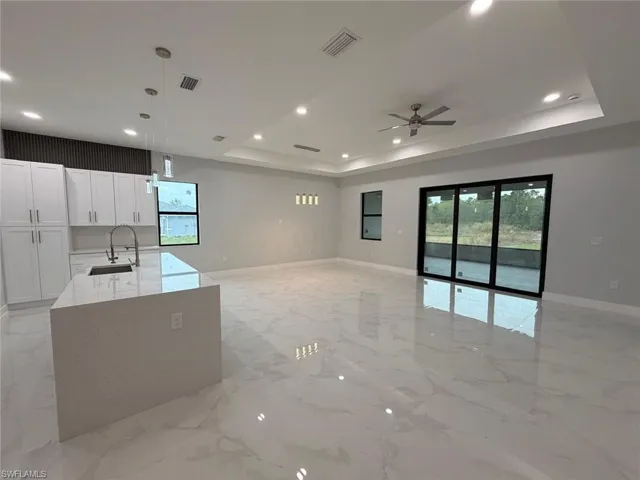 Kitchen featuring light stone counters, pendant lighting, healthy amount of natural light, light marble finish flooring, and recessed lighting