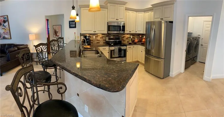 Kitchen with hanging light fixtures, appliances with stainless steel finishes, a kitchen breakfast bar, sink, and kitchen peninsula