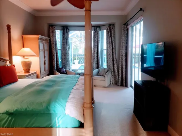 Carpeted bedroom featuring ceiling fan, crown molding, and multiple windows