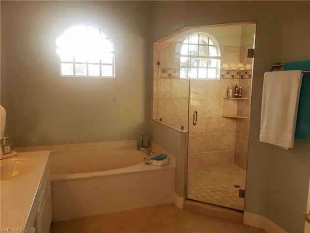 Bathroom with vanity, separate shower and tub, and tile patterned flooring