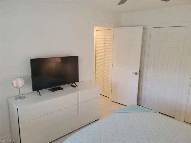 Guest Bedroom with tile floors, lighted ceiling fan, flat screen TV