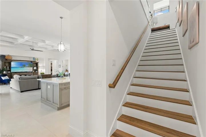 Stairs featuring coffered ceiling, ceiling fan, beamed ceiling, and tile patterned flooring