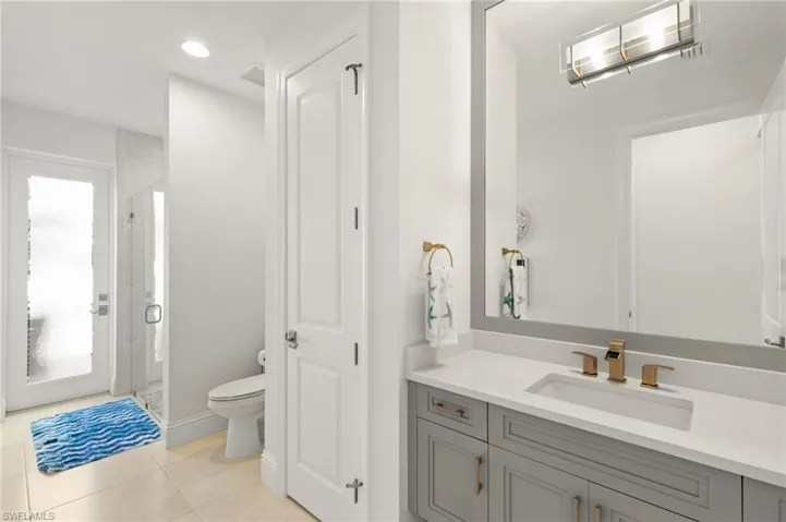 Bathroom with a shower stall, vanity, light tile patterned floors, and recessed lighting