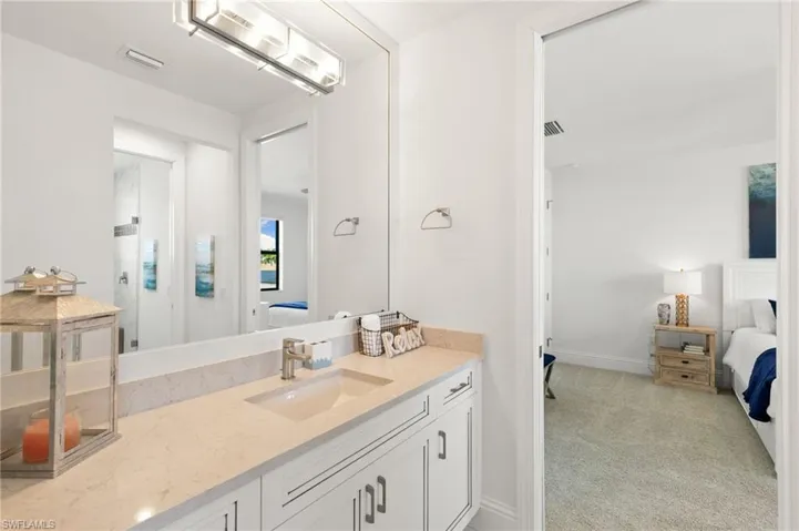 Bathroom with ensuite bath, vanity, and light carpet