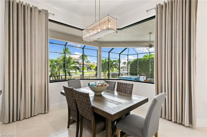Dining room with a sunroom, light tile patterned floors, ceiling fan, and a chandelier