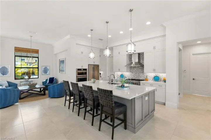 Kitchen with a kitchen breakfast bar, white cabinets, a large island with sink, backsplash, and recessed lighting