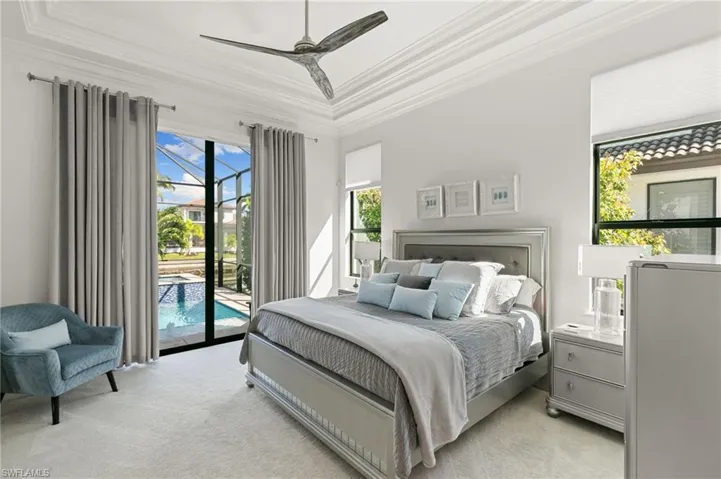 Bedroom featuring crown molding, access to exterior, multiple windows, light colored carpet, and a ceiling fan
