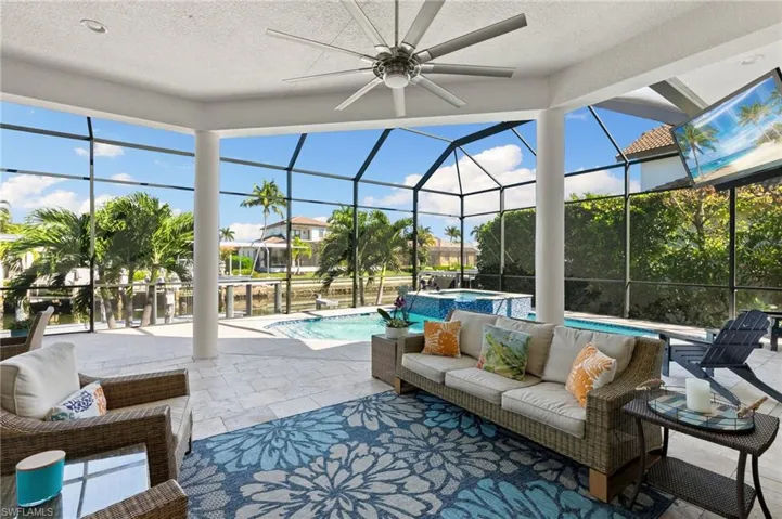 View of patio featuring a lanai, a sunroom, a pool with connected hot tub, outdoor lounge area, and a ceiling fan