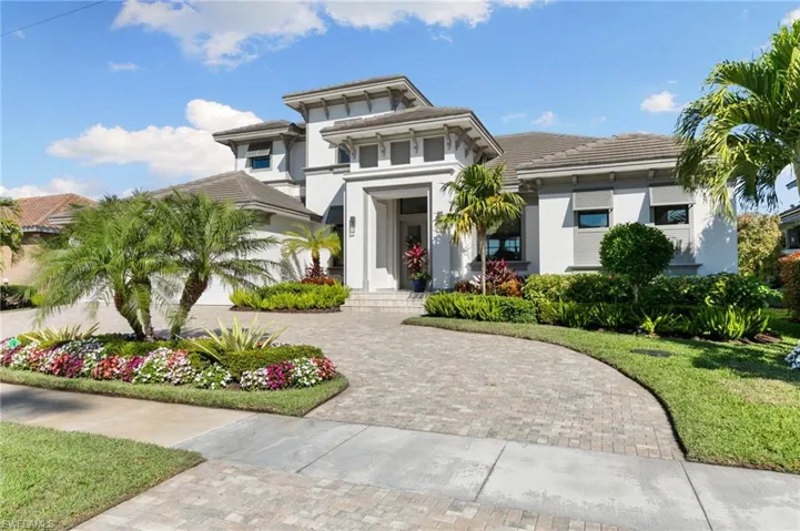 View of front of home with stucco siding, a tiled roof, a front lawn, and decorative driveway