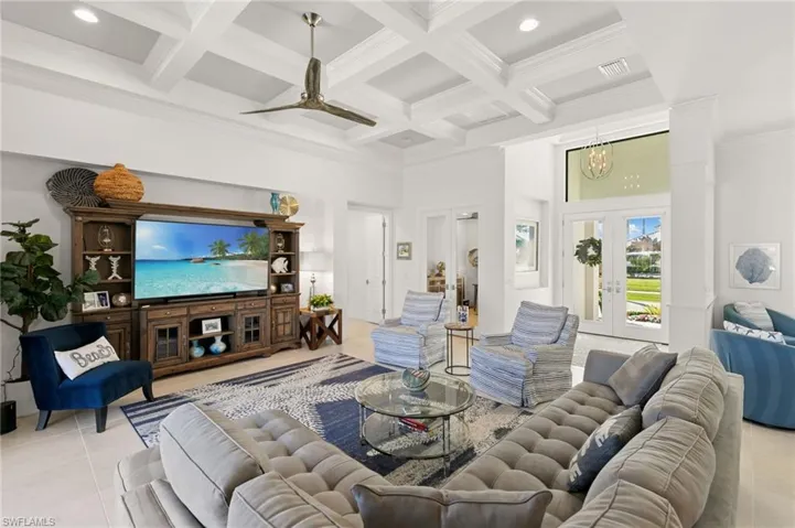 Living room featuring a high ceiling, french doors, light tile patterned floors, coffered ceiling, and beamed ceiling