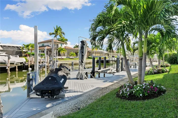 Dock with boat lift, a water view, a lawn, and a residential view