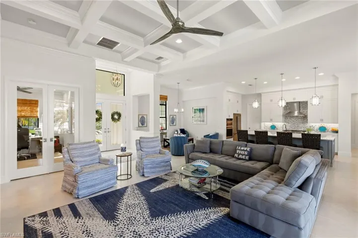 Living area featuring french doors, ceiling fan, ornamental molding, beam ceiling, and coffered ceiling