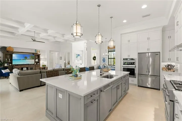 Kitchen featuring white cabinets, high quality appliances, decorative light fixtures, open floor plan, and coffered ceiling