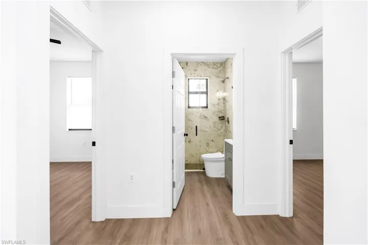 Neutral color palette throughout featuring wood-finish flooring, white walls, and dark hardware