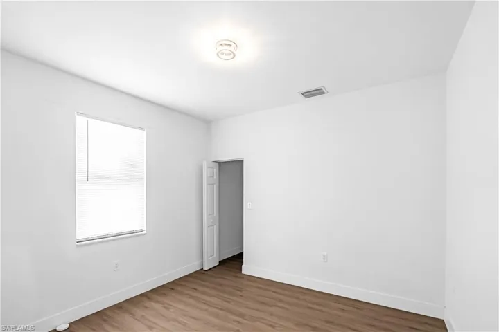 Bright room featuring wood-finish flooring, white baseboards, and a single window with blinds