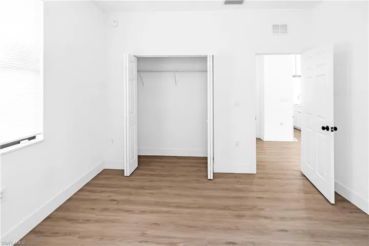 Room featuring wood-finish flooring, crisp white walls, and bright white baseboards