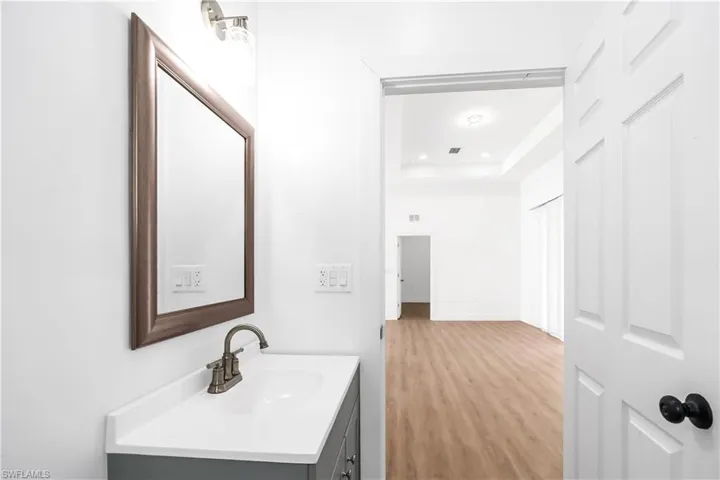 Bathroom vanity with a white rectangular sink, a two-handle faucet, and a framed mirror