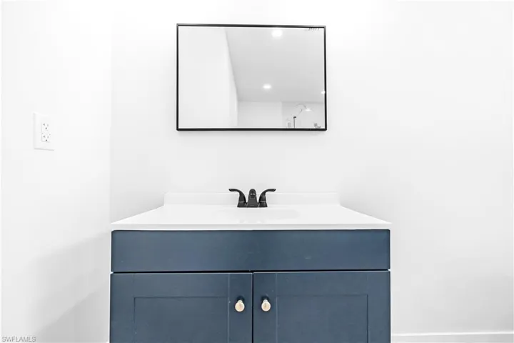 Vanity with a deep blue cabinet, white countertop, and integrated sink