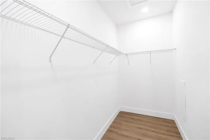 Walk-in closet featuring white wire shelving, recessed lighting, and wood-finish flooring