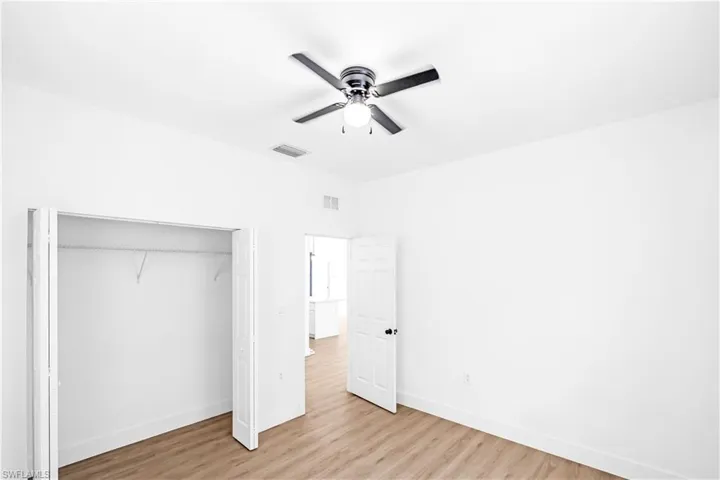 Room featuring wood-finish flooring, a ceiling fan with integrated lighting, and white walls