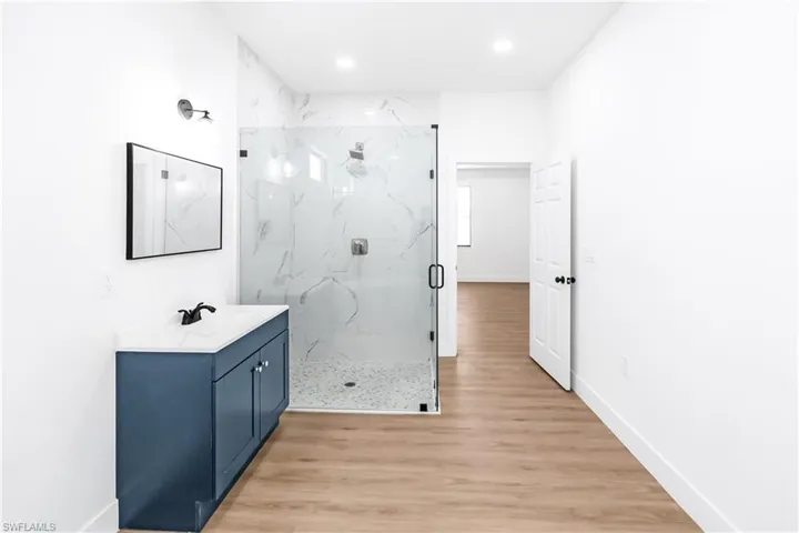 Bathroom featuring a blue vanity with a white countertop and a frameless glass shower enclosure