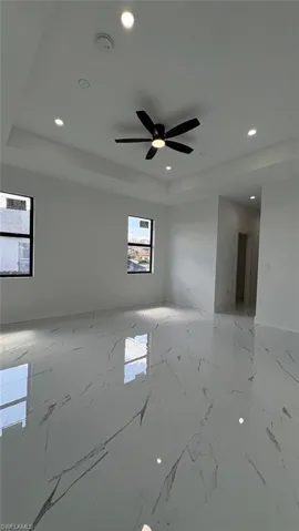 Empty room featuring marble finish floor, a tray ceiling, and recessed lighting