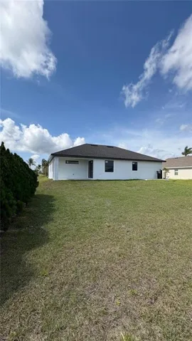 Rear view of house with a lawn and stucco siding
